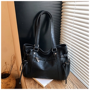 Detail of black leather tote bag featuring drawstring side pockets and silver zipper accents