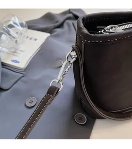 Close-up of silver metal hook and white contrast stitching on a dark brown leather bag