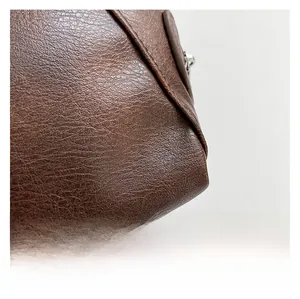 Close-up of deep brown pebbled leather texture with precise stitching and silver zipper