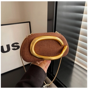 Detail view of brown woven acrylic clutch with large gold oval buckle and snake chain