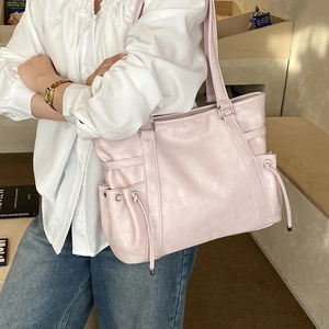 Detail of light pink faux leather tote bag with functional drawstring side pockets
