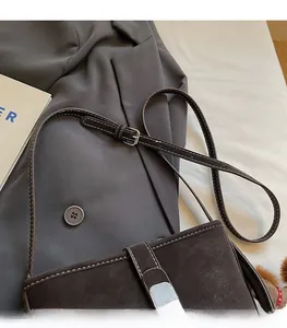 Detail of dark brown leather bucket bag showing white contrast stitching and adjustable strap