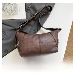 Detail view of deep brown litchi pattern leather bag with adjustable silver buckle strap