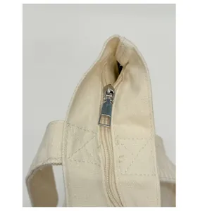 Details des Metallreißverschlusses und der verstärkten Nähte der beigen Canvas-Tasche