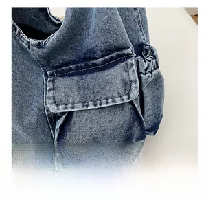 Close-up of side pocket on dark blue denim crossbody bag with visible stitching detail