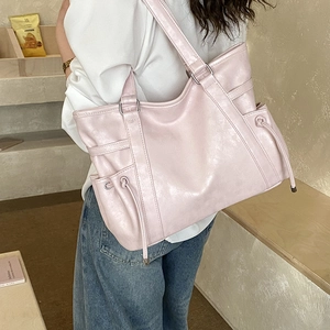 Detail of light pink tote bag featuring drawstring side pockets and silver hardware