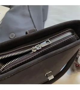 Close-up of smooth silver metal zipper and contrast stitching on dark brown bucket bag