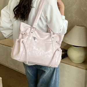 Detail view of the light pink tote bag featuring silver studs and side drawstring pockets