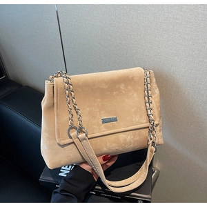 Détail du sac bandoulière en daim beige avec logo en métal argenté et chaîne
