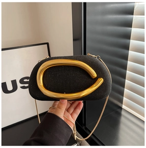 Detail of black glitter evening bag featuring a large gold C-shaped metal handle clasp