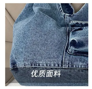Detail of blue denim shoulder bag showing twill texture and contrast stitching seams