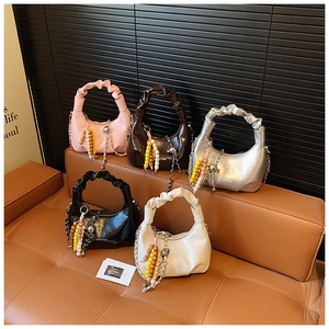 Detail of five stylish pleated crescent bags with beaded charms on a leather sofa