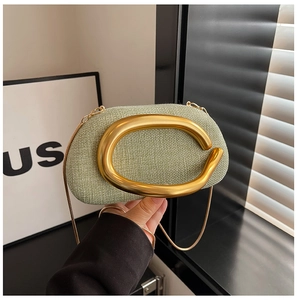 Detail of light green woven fabric bag featuring a matte gold ring and fine chain strap