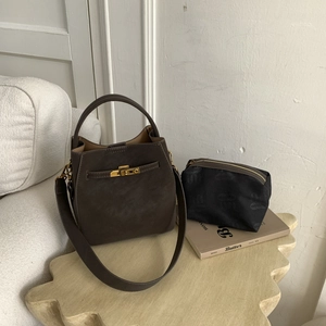 Detail of dark brown matte bucket bag with golden buckle and matching small printed pouch