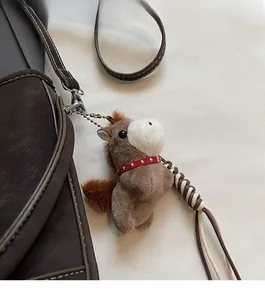 Detail of a brown plush horse charm with red collar attached to a bucket bag handle