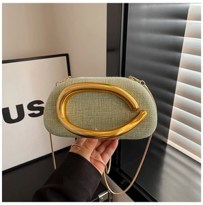 Detail of light green woven texture clutch with a large gold C-shaped metal handle