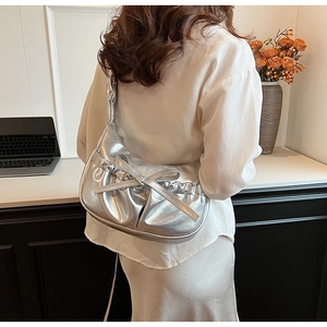 Borsa a spalla argento metallizzato con pieghe e grande fiocco indossata dal modello