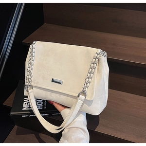 Détail du sac cabas en simili daim crème avec chaîne argentée et logo métallique