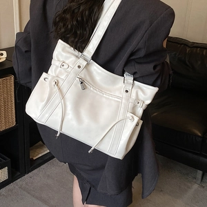 Detail of white glossy tote bag with front zipper and side drawstring pockets on model