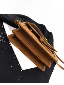 Detail view of brown lychee leather handbag featuring accordion gussets and contrast stitching
