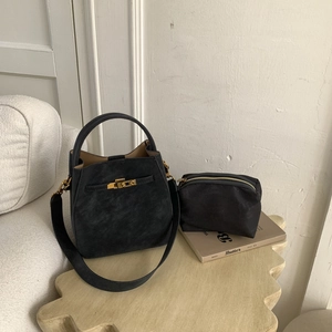 Detail of black matte bucket bag and zipper pouch with golden metal clasp hardware