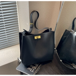 Détail du sac seau en cuir grainé noir avec un fermoir pivotant en métal doré poli