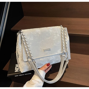 Détail du sac à bandoulière argenté avec logo métallique et chaîne en métal