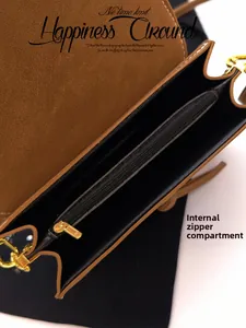 Interior view of tan leather shoulder bag with black lining and golden metal zipper pocket