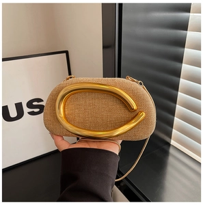 Close-up of khaki woven clutch featuring a large curved gold handle and fine metal chain
