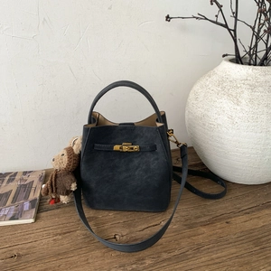 Detail of dark grey bucket bag with metal buckle on a wooden table with decor