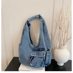Detail of vintage blue denim hobo bag with front pocket and pleated shoulder strap