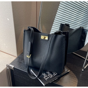 Detail of black pebbled leather bucket bag with a golden rectangular metal turn-lock clasp