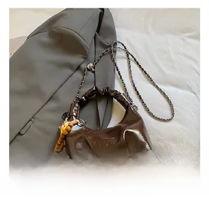 Detailed macro view of dark brown glossy patent leather texture and metal chain strap