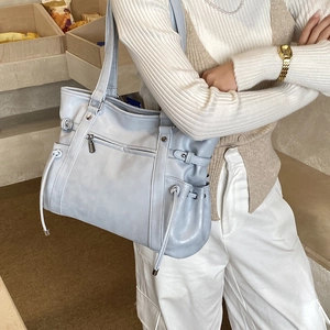Detail of light blue tote bag showing soft leather texture and functional side pockets