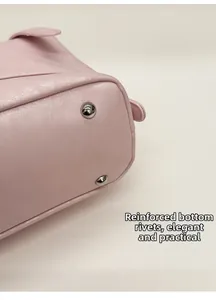 Detailed macro view of pink leather bag bottom featuring silver metal protective rivets