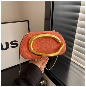 Detail of orange textured fabric crossbody bag with matte gold oval metal ring and chain