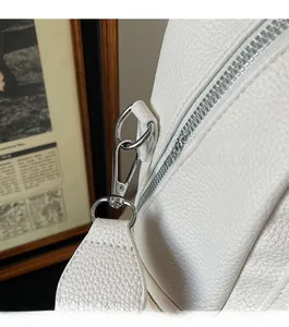 Detail view of white soft leather texture with silver lobster clasps and metal zippers