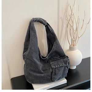 Detail of black washed denim tote bag with oversized utility pocket and wide strap