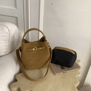 Detail of tan leather bucket bag with metal lock closure and black zip pouch insert