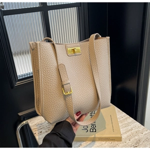 Détails d'un sac cabas en cuir beige à motif lychee avec boucle dorée et bandoulière