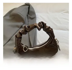 Close-up of ruched handle on dark brown patent leather bag with colorful beaded charm