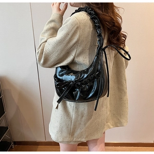 Detail of black pleated crescent bag with bow drawstring and wide shoulder strap