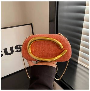 Detailed close-up of orange woven texture and large gold C-shaped metal hardware on bag