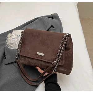 Gros plan d'un sac en daim marron rétro avec chaîne argentée sur un blazer gris