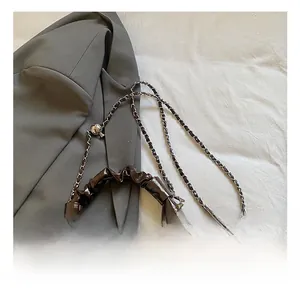 Detail of dark brown glossy pleated handbag with silver chain and colorful wooden beads
