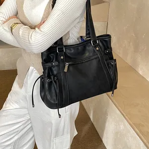 Detail of black PU leather tote bag with side drawstrings and front zipper pocket