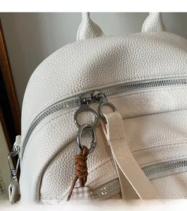 Detail of silver metal zipper with round puller on white litchi pattern backpack