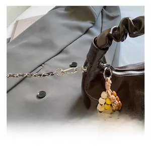 Detail view of dark brown wrinkled patent leather bag with silver hooks and bead charm