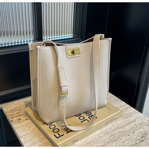 Détail du sac cabas en cuir crème avec boucle en métal doré sur marbre