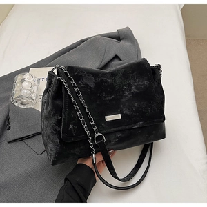 Gros plan du sac fourre-tout noir texturé avec chaîne argentée sur un blazer